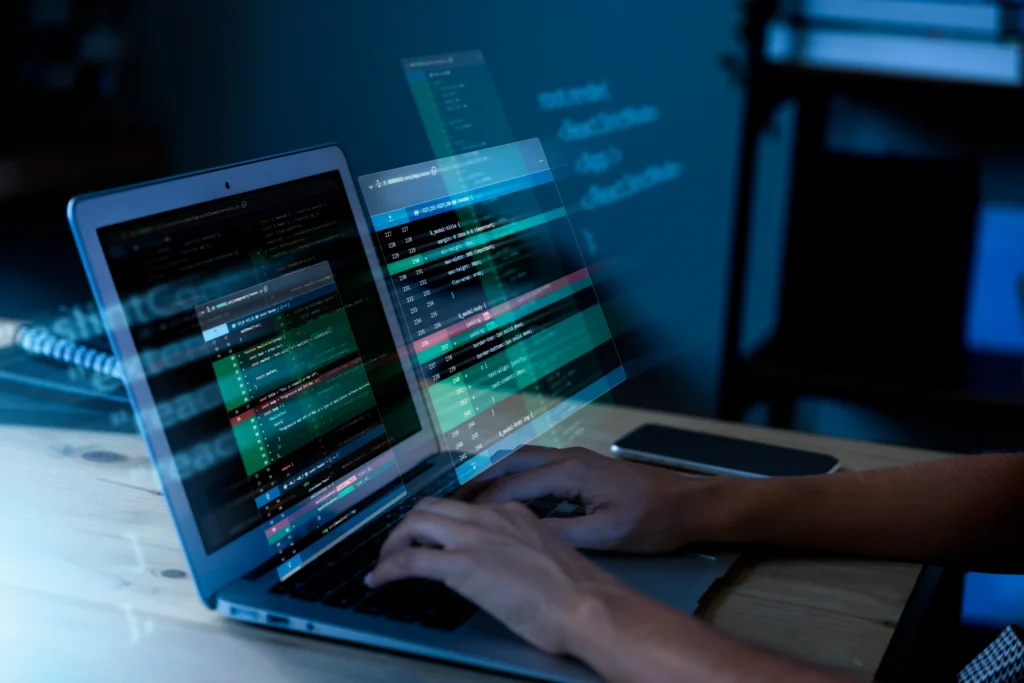 Hands coding on a laptop with translucent holographic code windows floating above.