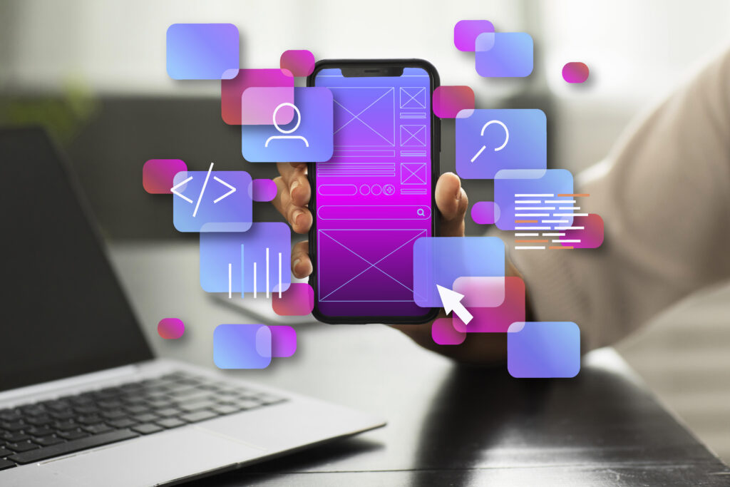 Hand holding a smartphone mock-up surrounded by floating colorful app icons next to a laptop.